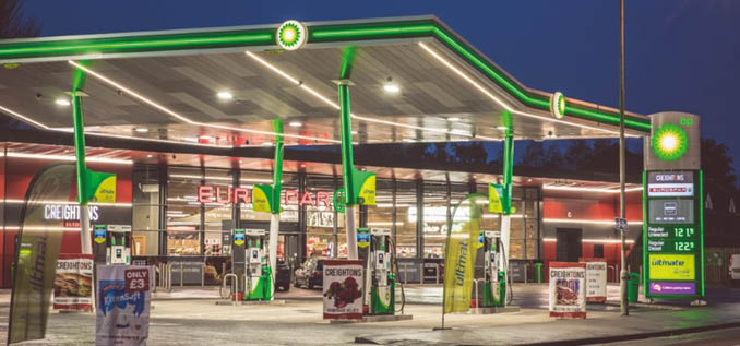 A gas station with green and red colors and a lit up sign. AI generated content