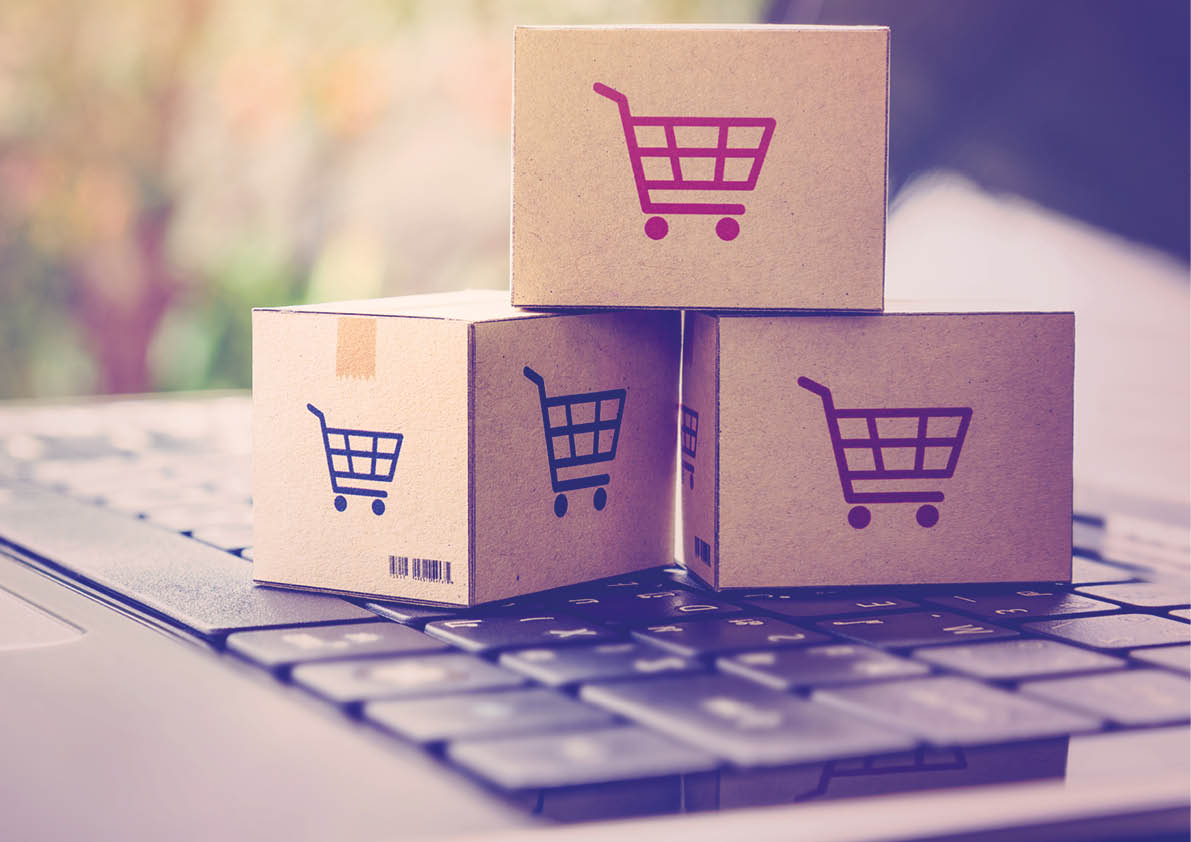 Online shopping / ecommerce and delivery service concept : Paper cartons with a shopping cart or trolley logo on a laptop keyboard, depicts customers order things from retailer sites via the internet.