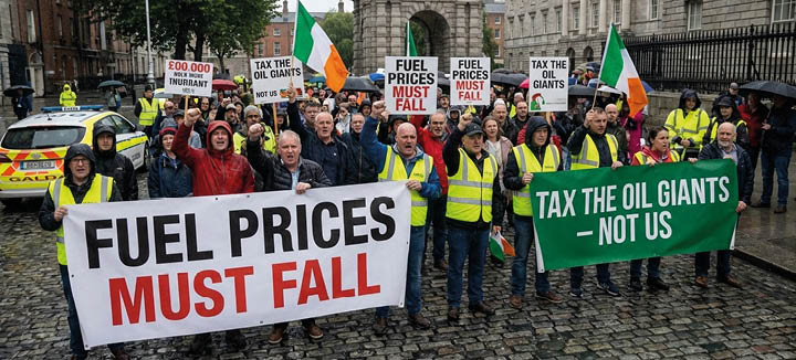 A group of people holding signs that say fuel prices must fall. Description generated by AI