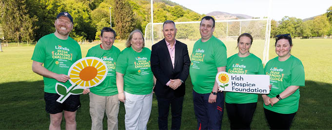 A group of people wearing green shirts and holding up signs. Description generated by AI