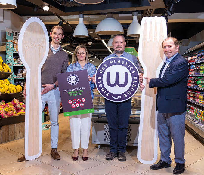 Three people are standing in front of a display of plastic forks. Description generated by AI