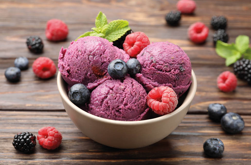 A bowl of purple berries and raspberries with a blueberry on top. Description generated by AI