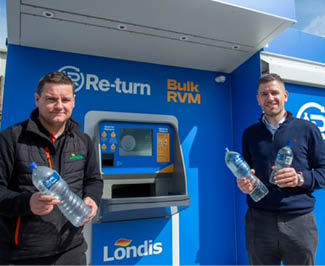 Two men standing in front of a blue and yellow machine. Description generated by AI