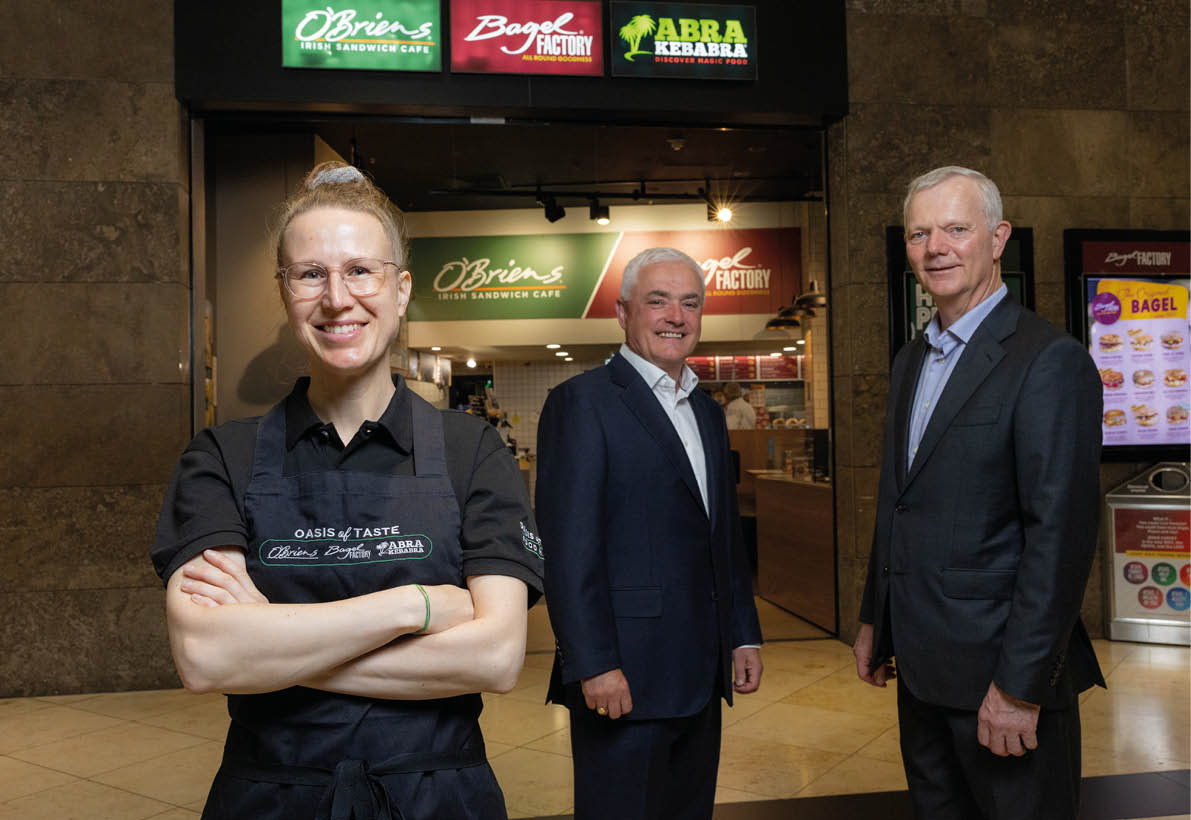 Three people standing in front of a restaurant. Description generated by AI