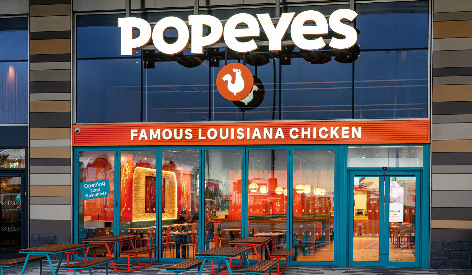 A Popeyes restaurant with a red and orange sign. Description generated by AI