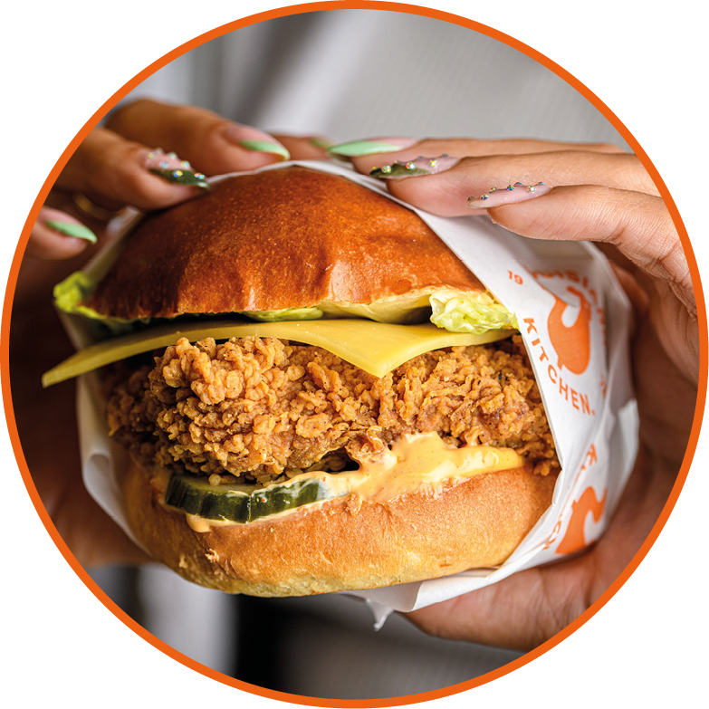 A person holding a sandwich with lettuce and cheese. Description generated by AI