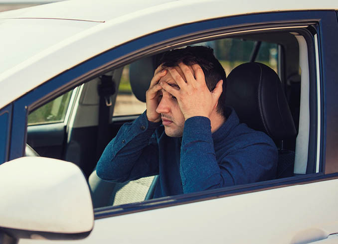 Stressed young man driver, pissed off keeps hands to head covering face, has problems with the broken car. Unlucky guy has a road accident or forgot to fuel up his car.