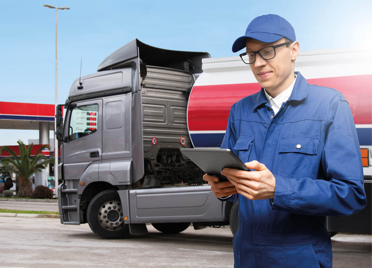 Man with digital tablet on a background of gasoline truck with tank trailer and a gas station