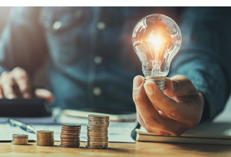 business man hand holding lightbulb with using calculator to calculate and money stack. idea saving energy and accounting finance in office concept