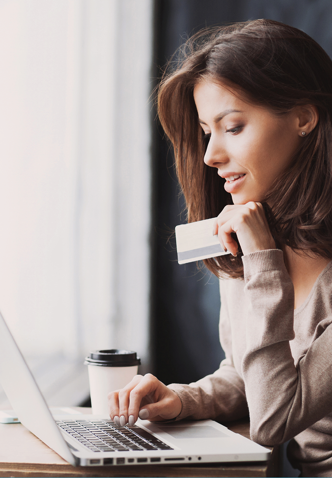 Young woman holding credit card and using laptop computer. Businesswoman working at home. Online shopping, e-commerce, internet banking, spending money, working from home concept