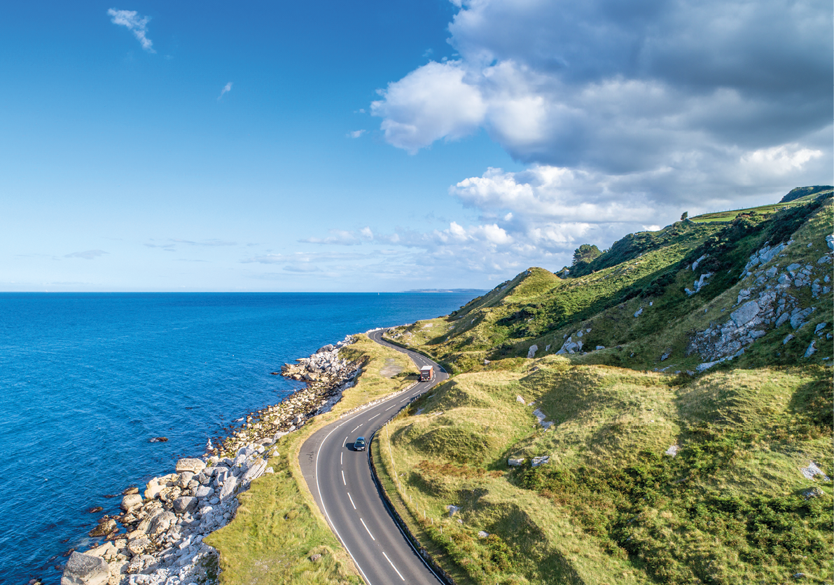 Causeway Coastal Route with cars, a.k.a. Antrim Coastal Road on eastern coast of Northern Ireland, UK.