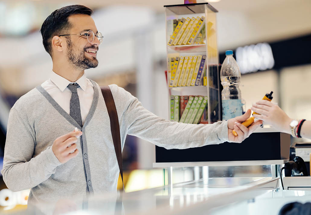 A happy young man is choosing vape at shopping mall.