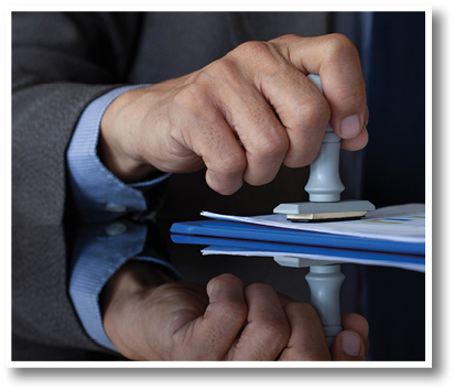 Businessman in suit hand stamping rubber stamp on document at office. Authorized allowance permission approval concept.