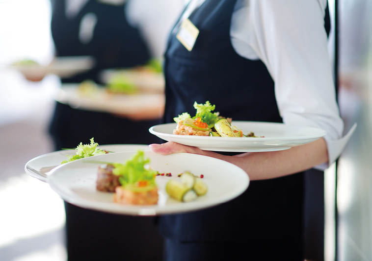 Waiter carrying plates with meat dish on some festive event, party or wedding reception 