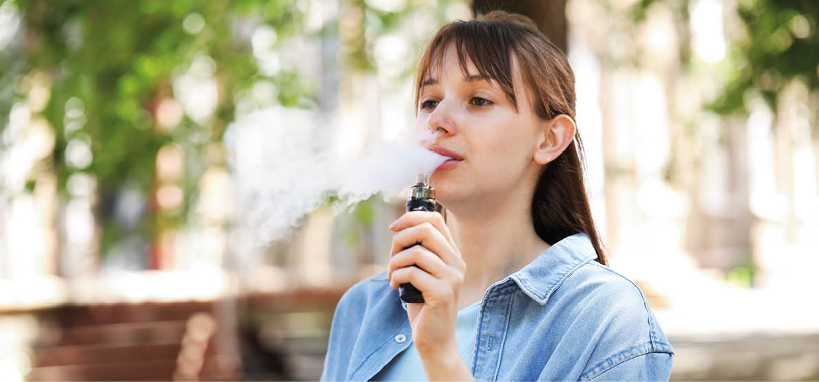 Young woman using electronic smoking device outdoors. Space for text