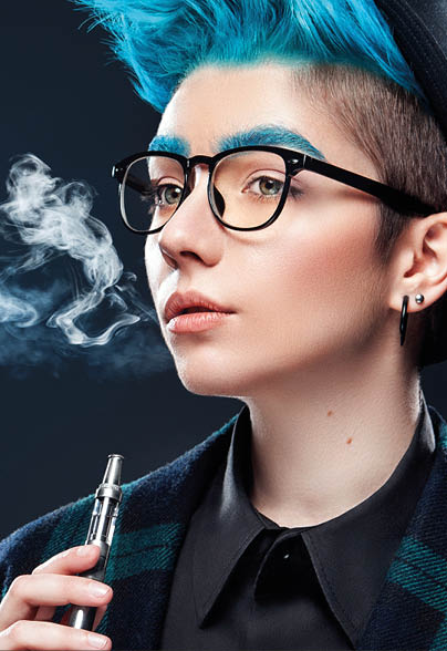 hipster woman with blue hair smoking fruit electronic cigarette on black background. Vape advertisement concept. Copy space