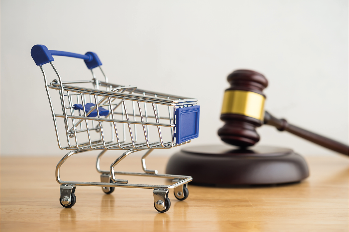 Shopping trolley cart and hammer judge gavel on wooden table with white wall background copy space. Consumer rights and and responsibilities to safety, customer protection, commercial law concept.