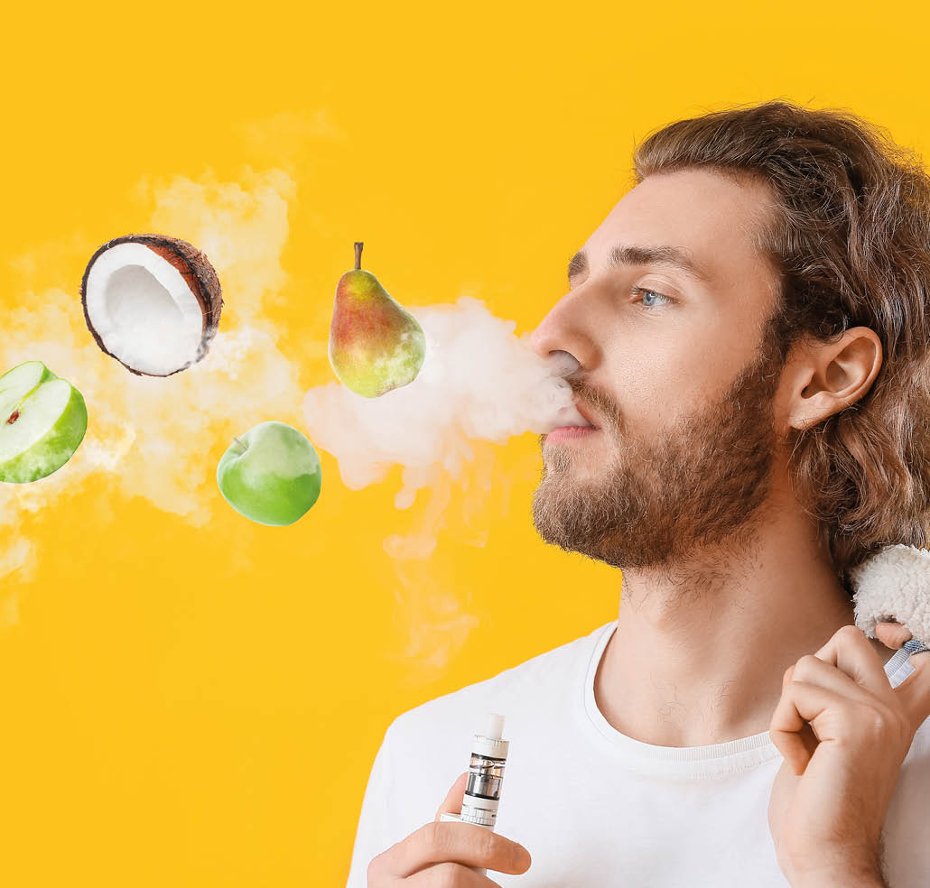 Young man smoking electronic cigarette with fruit flavor on yellow background