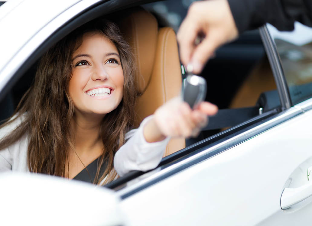 Young woman receiving the keys of her new car